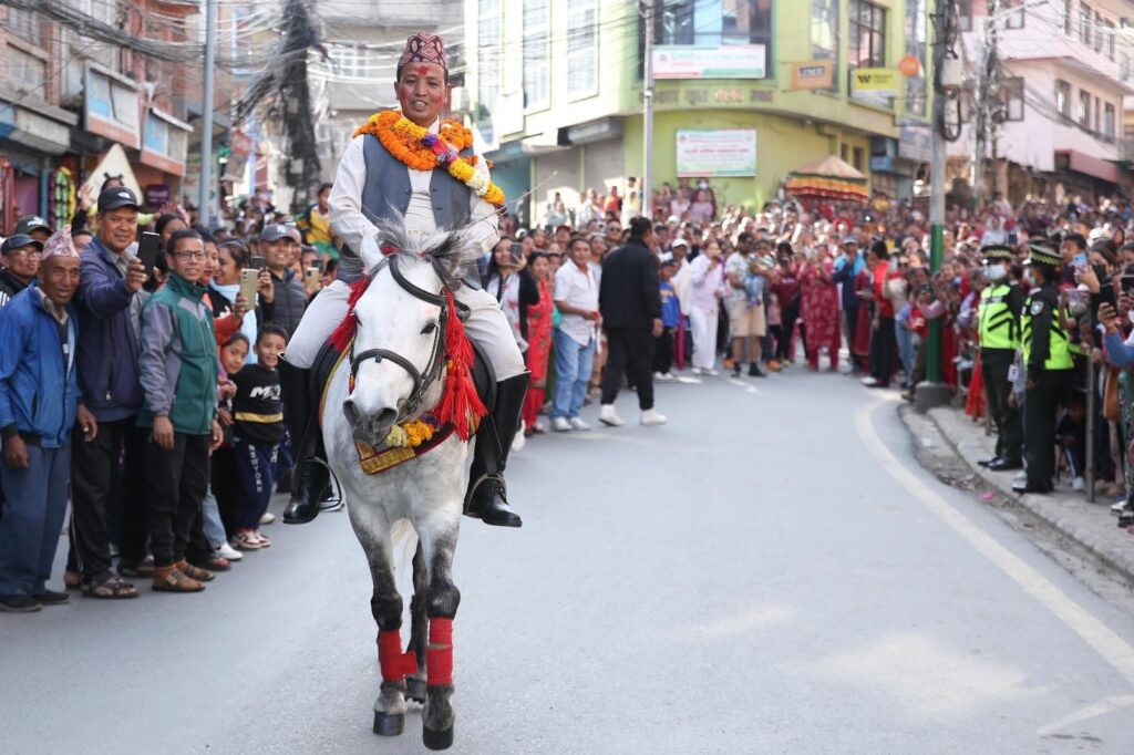 Ghode Jatra celebration in Balkumari, Lalitpur A rider dressed in traditional Nepali costume, a full white skirt, ash coat, white trouser, riding boot and Nepali topi (cap), riding a horse with red socks.